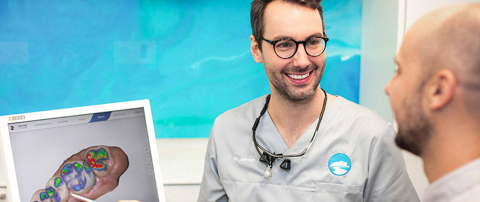 Zahnarzt Peter Jordan mit Patienten vor Monitor