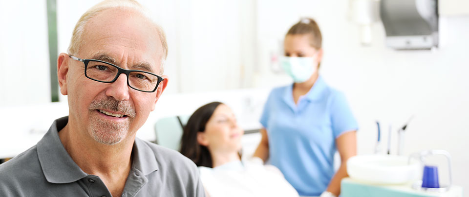Zahnarzt Andreas Jordan im Behandlungsraum mit Patientin und Assistentin